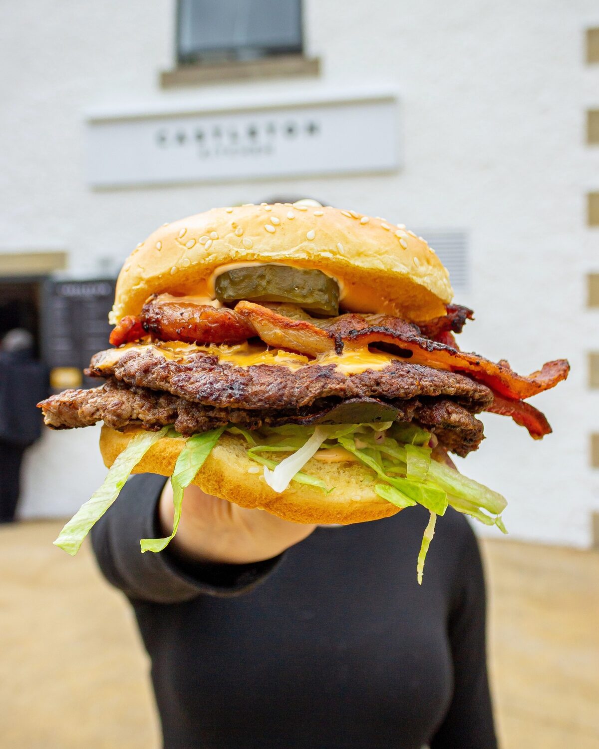 A loaded Peak Burger Co smash burger held up outside the Castleton Visitor Centre
