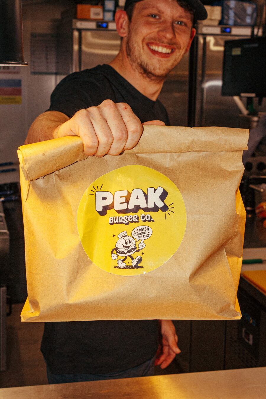 Peak Burger Co team member holding a branded takeaway bag