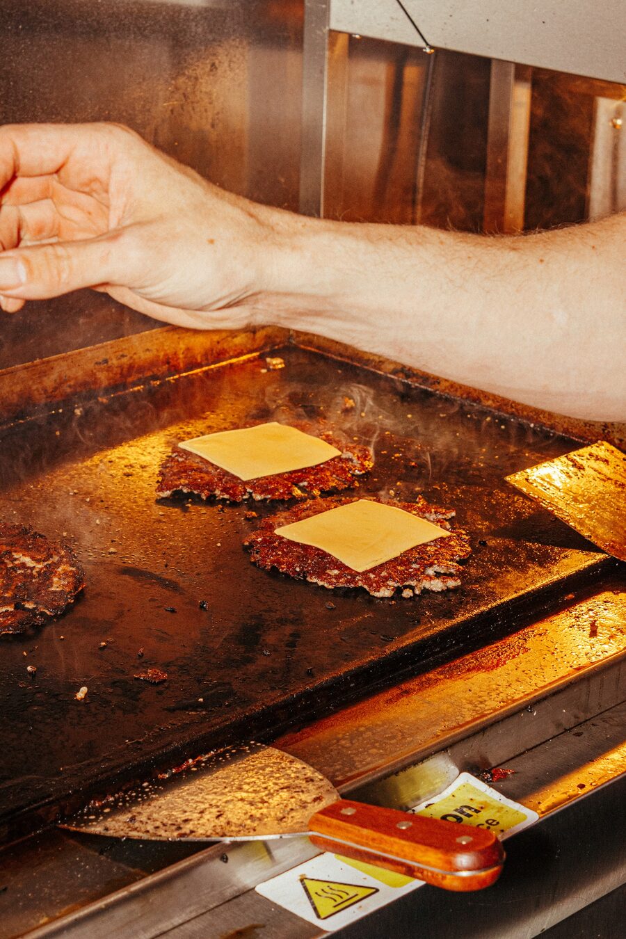 Beef patties with melting cheese on the griddle at Peak Burger Co